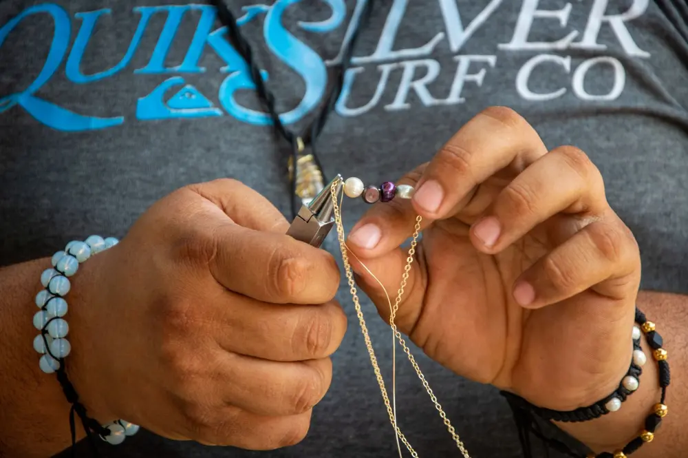 Hands stringing a beaded necklace