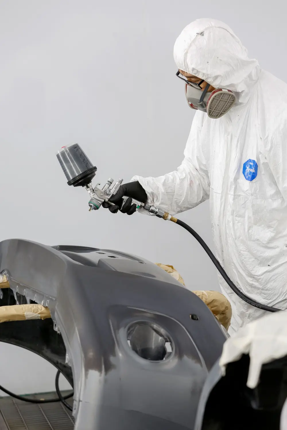 Technician spray painting a bumper