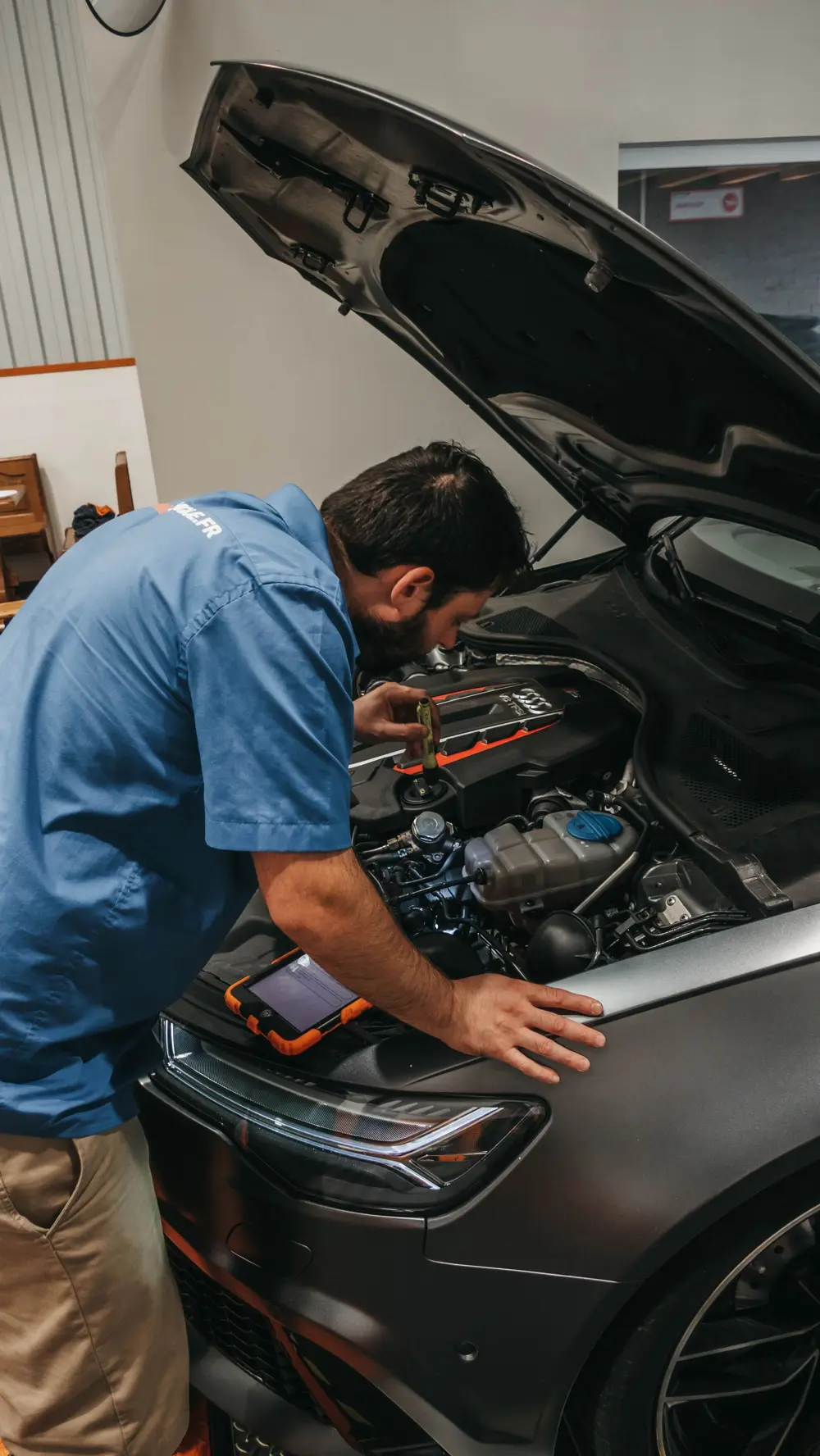 Mechanic checking an engine under an open hood
