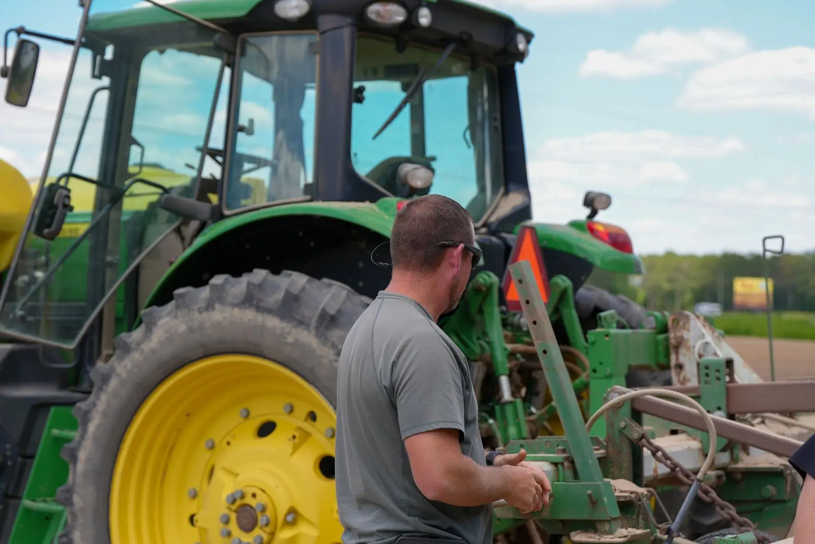 Mechanic working beside a green tractor on a farm