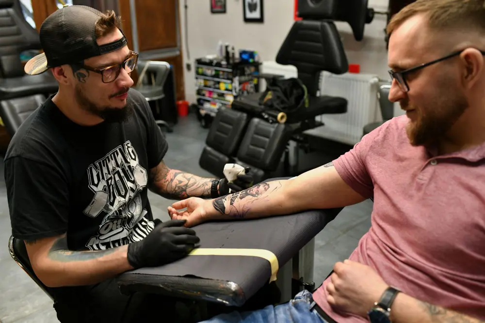 Tattoo artist working with a client